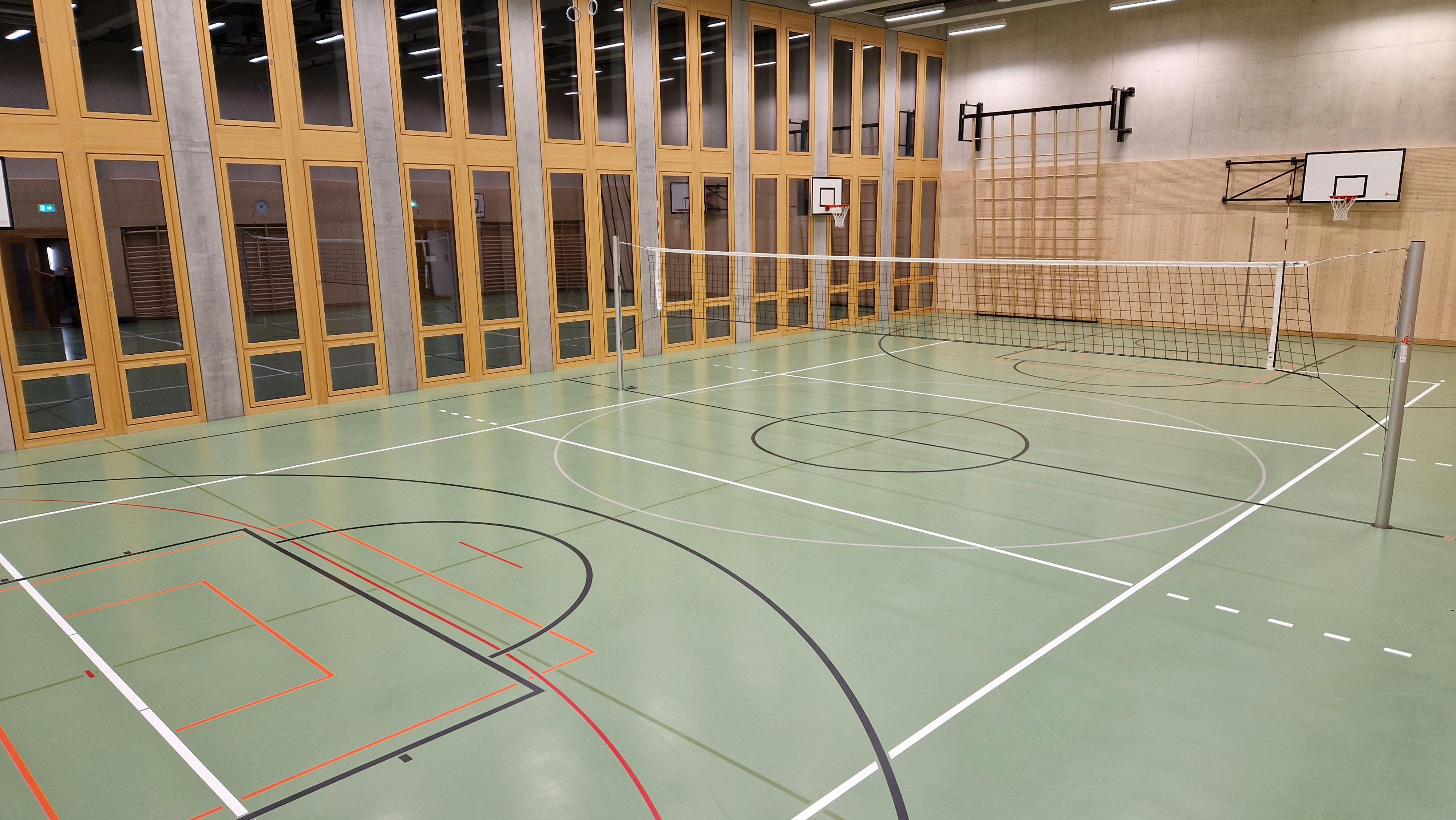 Innenansicht der Turnhalle im Schulhaus Schütze mit Volleyballnetz und Sportboden